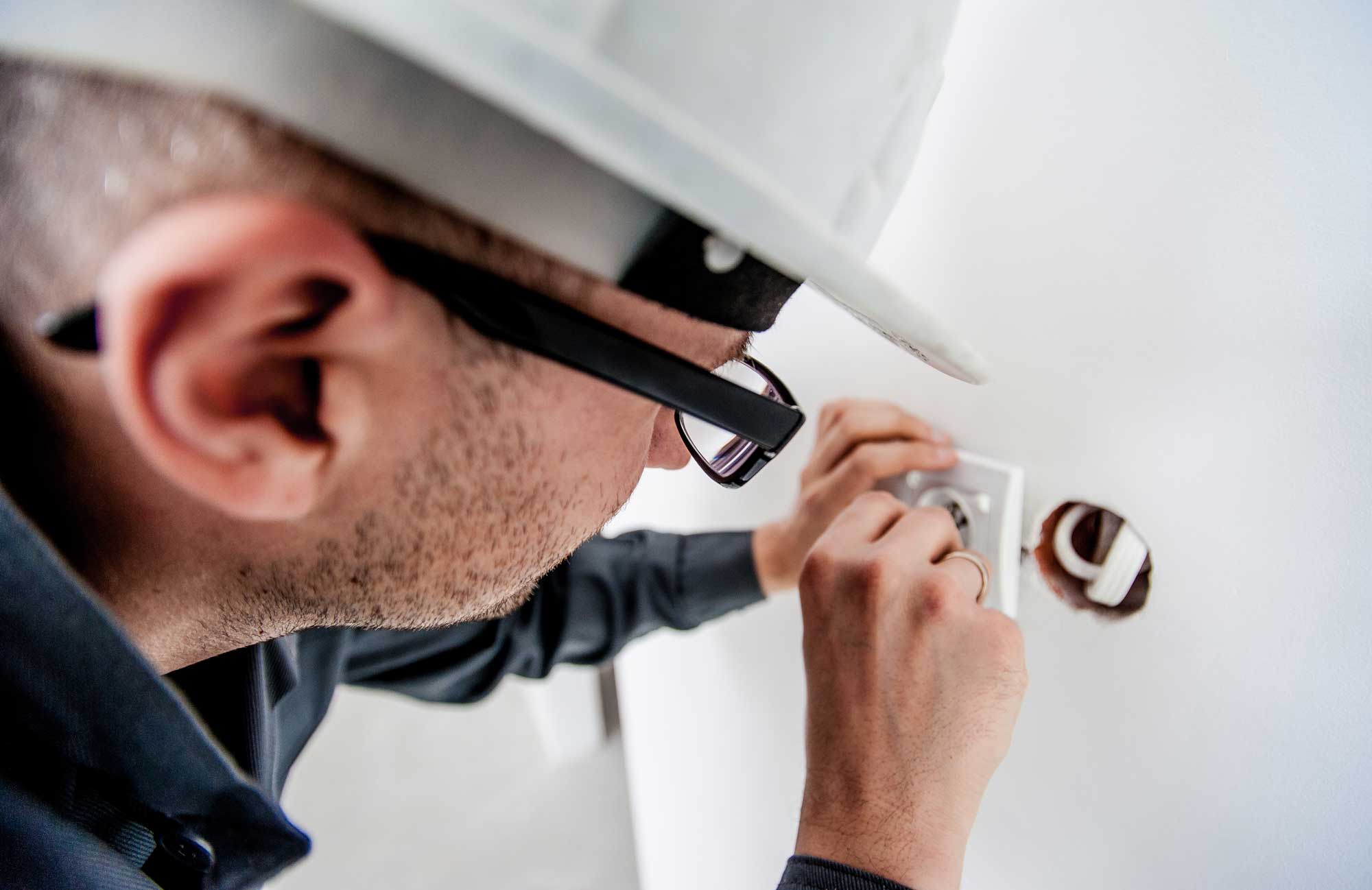 Elektromeister mit helm installiert weiße Steckdose